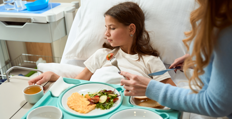 stock-photo-mom-helps-her-daughter-in-a-hospital-bed-with-a-meal